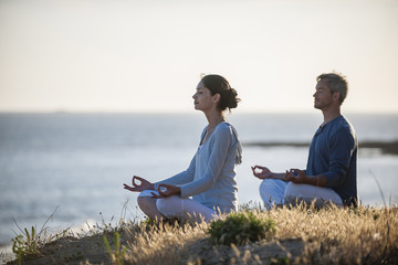 handsome couple practicing meditation exercises on the beach at