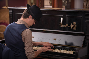 Portrait of a musician in suit and in black hat playing the pian