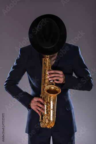 Fototapeta na wymiar Portrait of a jazz man in a suit with a hat hiding his face and