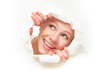 woman peeking through a  hole torn in white paper