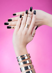 Woman with black manicure wearing gold bracelet and rings