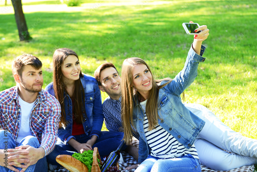 Happy friends on picnic in park