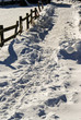 way in snow beside an fence, bright sun