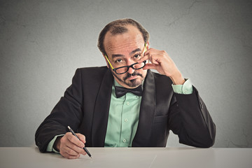 man with glasses skeptically looking at you sitting at desk