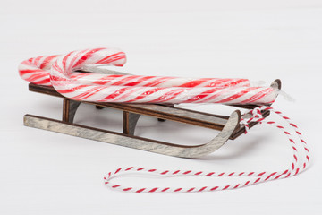 Christmas Candy Cane On Wooden Sledge. White Painted Wood Backgr