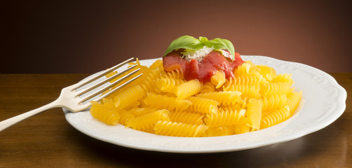 dish with macaroni and tomato sauce on the wooden table