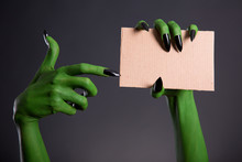 Green Monster Hand With Black Nails Pointing On Blank Piece Of C