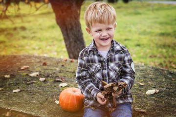 Wall Mural - Autumn. Beautiful smiling blond boy holds a leaf