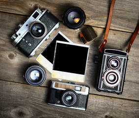 Canvas Print - Vintage cameras with lenses and blank old photograph on wooden b