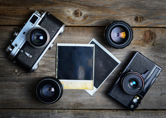 Canvas Print - Vintage cameras with lenses and blank old photograph on wooden b