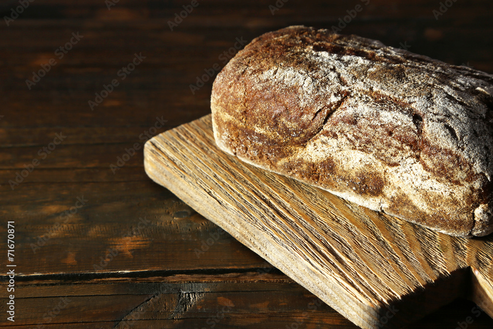 Rye bread on cutting board on wooden background