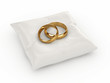 A pair of gold wedding rings on top of a pillow