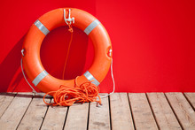 Lifebuoy Stands On Wooden Floor Nearby Red Wall Of Lifeguard Sta