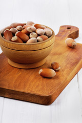 Wall Mural - Hazelnuts in a wooden bowl on a brown board