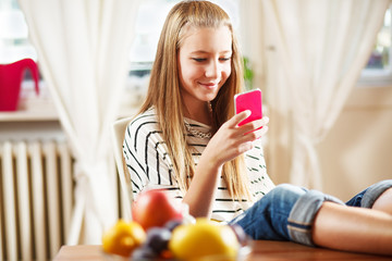 teenage girl texting message, on mobile phone, at home