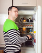 © DariaTrofimova - Guy searching for something in refrigerator