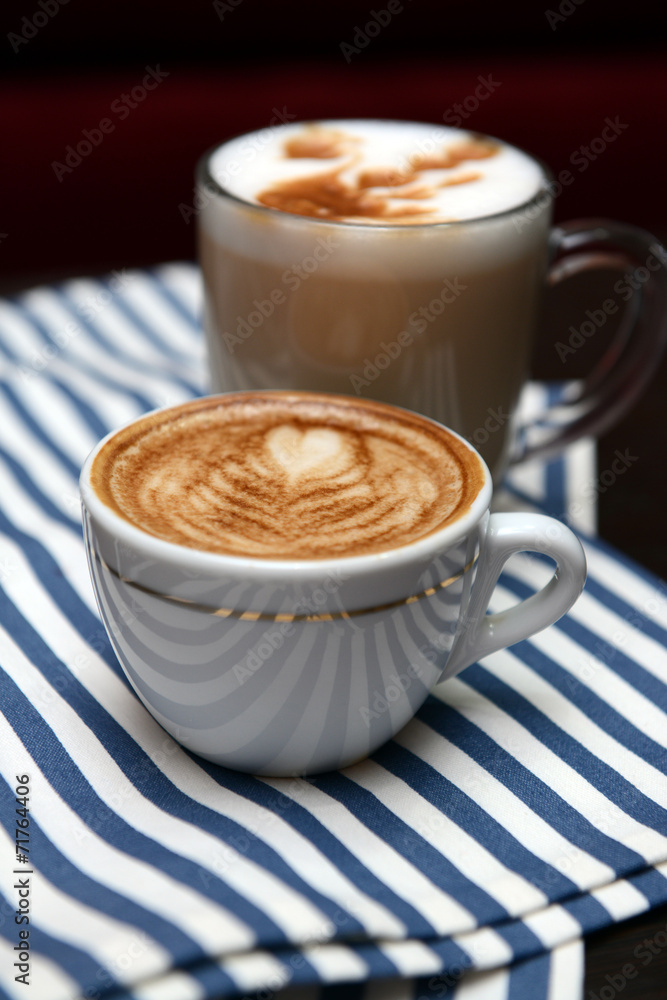 Cups of coffee with cute drawing in cafe