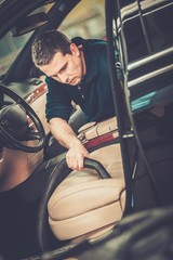 Wall Mural - Worker on a car wash cleaning car interior with vacuum cleaner