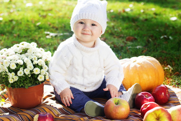 Baby boy with pumpkins in autumn park