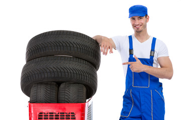 Cheerful mechanic pointing in new tires