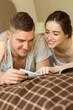 © WavebreakMediaMicro - Cute couple reading newspaper in bed