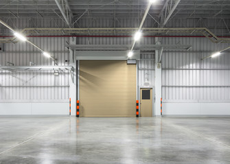 Roller door or roller shutter inside factory, warehouse or industrial building. Modern interior design with polished concrete floor and empty space for product display or industry background.