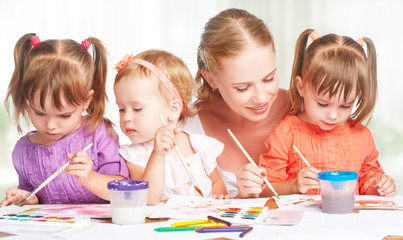 Wall Mural - children twin sisters draw paints with mother in kindergarten