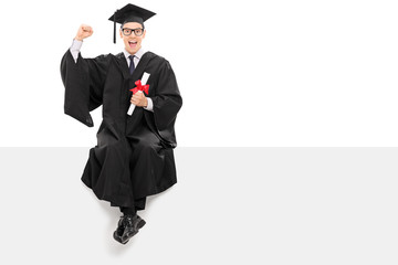 Canvas Print - College graduate holding a diploma seated on panel