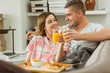 © WavebreakMediaMicro - Cute couple relaxing on couch with breakfast