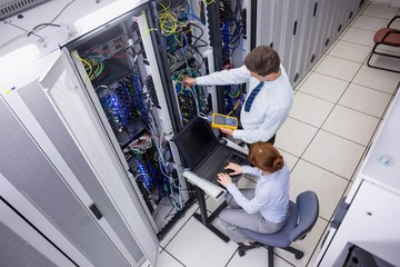 Fototapete - Team of technicians using digital cable analyser on servers