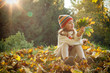 Cute child playing with autumn leaves