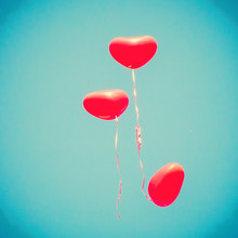 Three Red Heart-shaped Balloons Flying Away