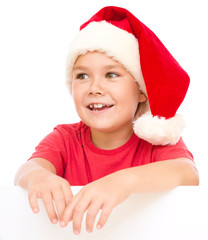 Little girl in santa hat is holding blank board