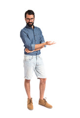 Wall Mural - Young hipster man presenting something over white background