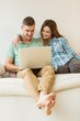© WavebreakMediaMicro - Cute couple relaxing on couch with laptop