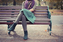 Young Woman Sitting On A Park Bench
