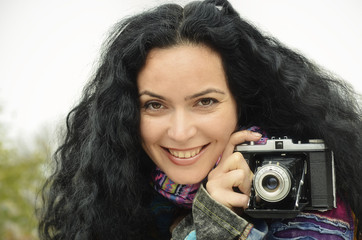 Young beautiful brunette woman holding an old, vintage photo camera