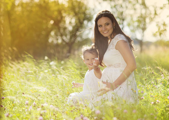 Wall Mural - Pregnant mother with her little daughter in nature