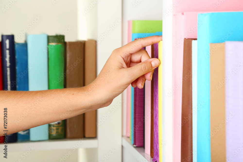 Hand picking book in library