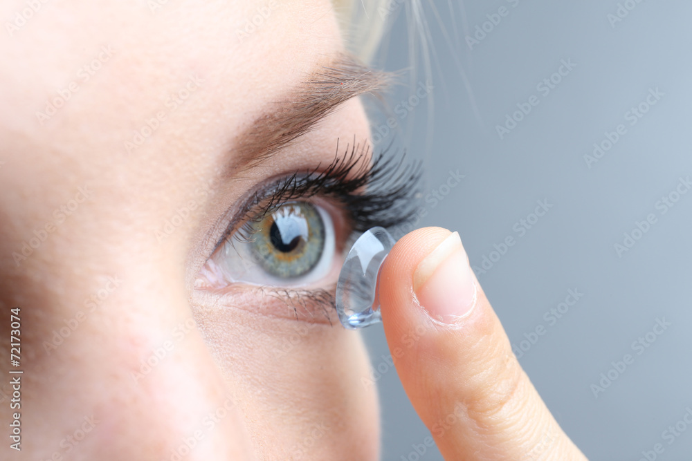 Medicine and vision concept - young woman with contact lens, - obrazy, fototapety, plakaty 