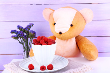 Wall Mural - Toy bear with flowers and cup of raspberries