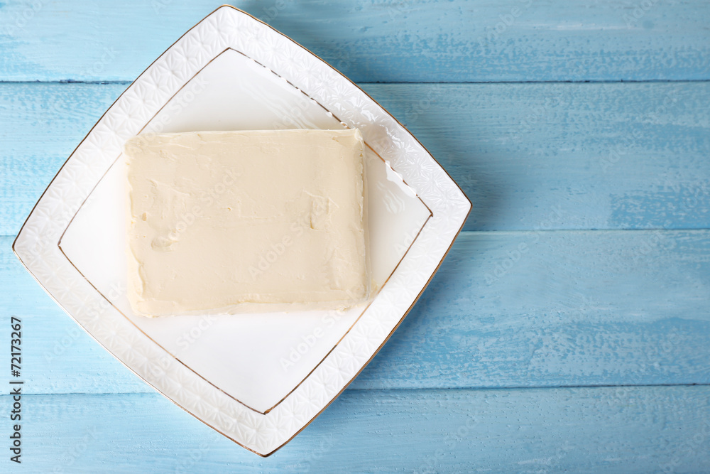 Fresh butter on plate, on wooden background