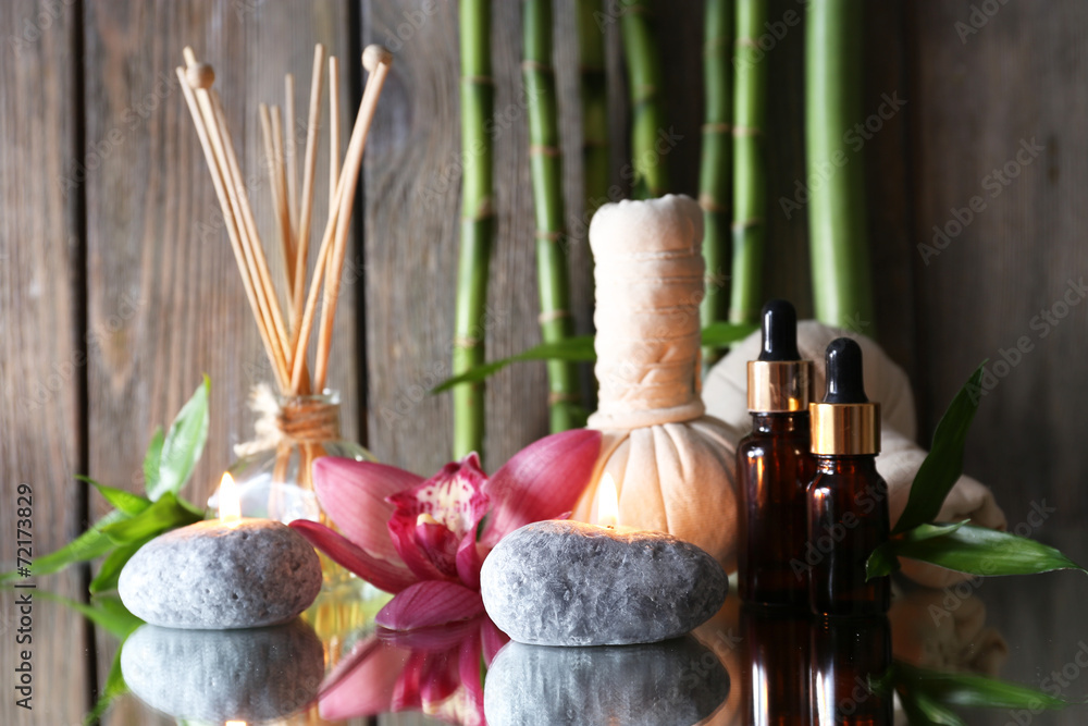 Spa set on mirror surface on wooden wall background