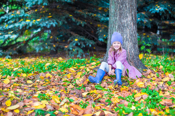 Little happy girl in autumn park on sunny fall day