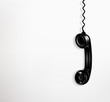 Black hanging telephone receivers on a white background.