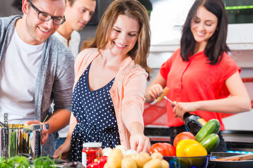 Fotografie, Obraz Freunde kochen Pasta und Fleisch zuhause in Küche