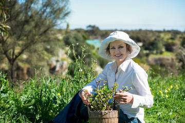 A mature woman  with plant in pot outdoors