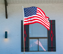 American Flag Reflecting In The Window Of A Storefront