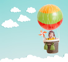 Cute Kid On Hot Air Balloon In The Blue Sky