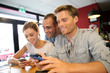 © goodluz - Young people in campus lounge connected on smartphone
